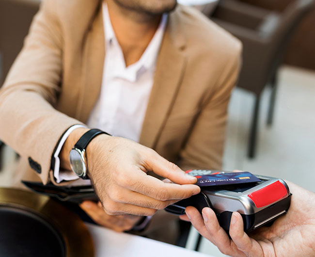 Close-up of young man in Fargo, ND, tapping his credit card to pay at a local business that uses Gate City Bank merchant services