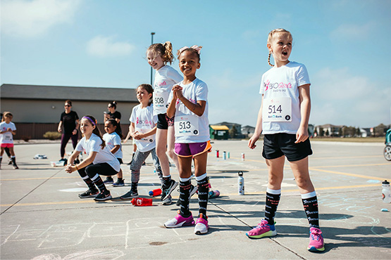 A group of happy BIO Girls and their mentors get ready to take part in a non-competitive physical activity on a sunny day