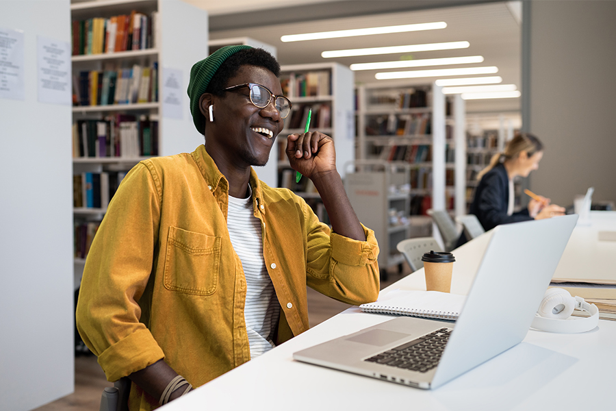 Bison student wearing a green beanie and glasses, laughing at the NDSU library in Fargo, ND