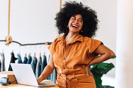 a happy business owner tilts her head back and smiles after reading Gate City Bank’s article on how to write a business plan