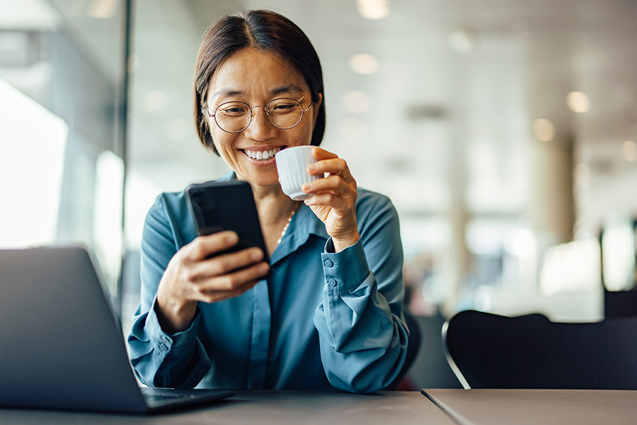 Forty-year-old businesswoman with wire-rimmed glasses, smiling as she compares Gate City Bank business checking accounts on her smartphone
