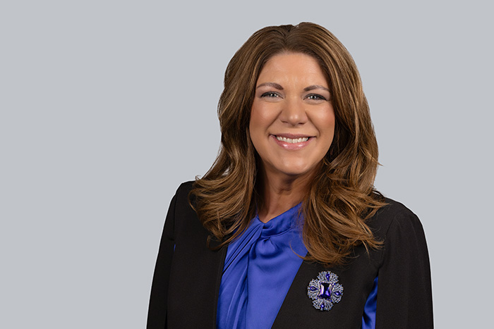 Kim Settel smiles for the camera while wearing a black blazer