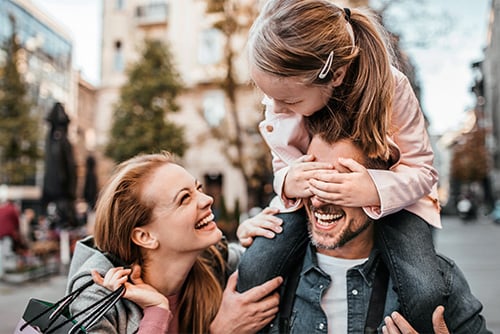 Family of three laughing and shopping together while strolling around downtown Grand Forks, ND, on a crisp fall day