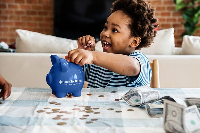 Five-year-old boy counts pennies and dollar bills beside his piggybank at his family’s home in Moorhead, MN