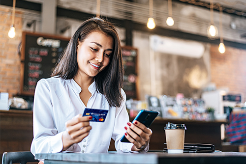 Young woman paying for coffee on her smartphone without any worries, thanks to Gate City Bank overdraft protection