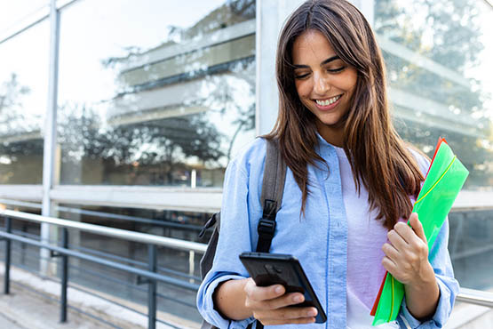 A gen Z woman monitors her finances by setting bank alerts on her smartphone outside her North Dakota office.