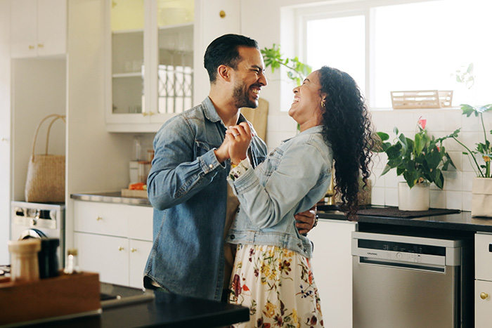 A young couple dances in their Fergus Falls, MN, kitchen after applying for the Mortgage Rate Relief program
