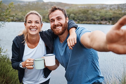 Happy couple smiling for a selfie while camping at the edge of Lake Geneva near Alexandria, Minnesota