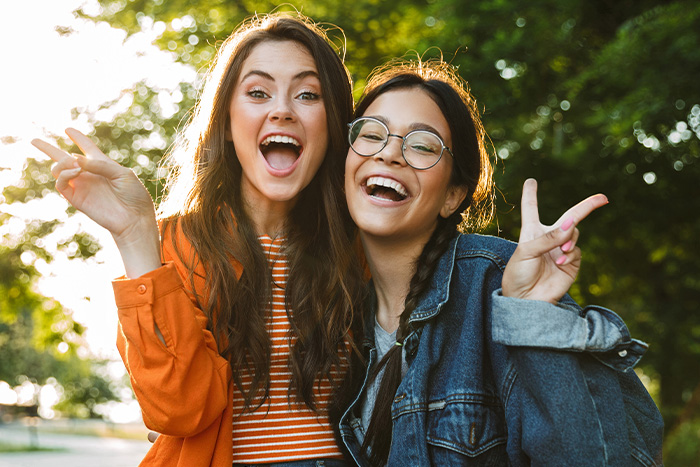 Two smiling young girls making peace signs while walking to Gate City Bank in Fargo, ND, to open new checking accounts 