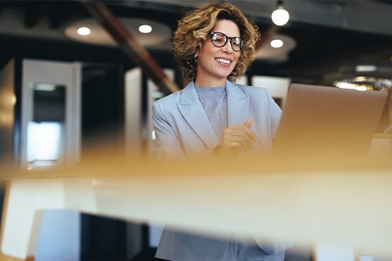 a happy businesswoman uses her laptop after learning 4 areas of fiduciary responsibility from Gate City Investment Services