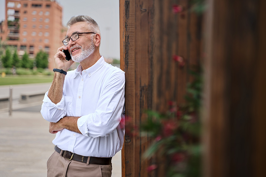 Relaxed 50-year-old executive standing outside his office in downtown Fargo, ND, talking on the phone with his business lender
