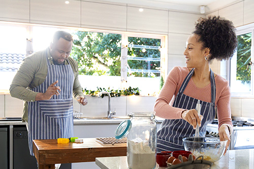 Couple in matching aprons cooking in their Fargo, ND, kitchen after buying a home with Gate City Bank’s mortgage rate match guarantee