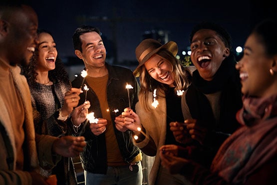 Group of friends laughing in downtown Fargo, ND, holding sparklers to celebrate opening their new Gate City Bank checking accounts