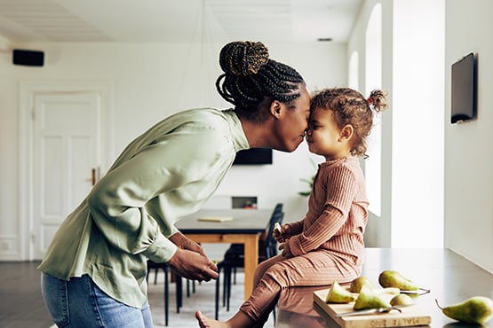 Loving mom touches noses with her preschool age daughter in a new kitchen, thanks to a Gate City Bank home loan in Fargo, ND