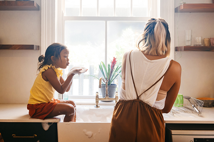 A mother and her young daughter have fun while washing dishes in their Waite Park, MN kitchen after buying a new home in 2026