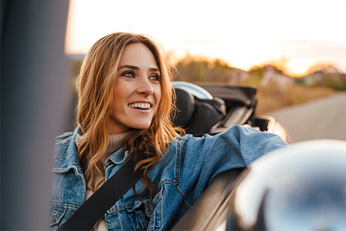 woman smiling and driving her new convertible at sunset after getting an auto loan from Gate City Bank in Moorhead, MN