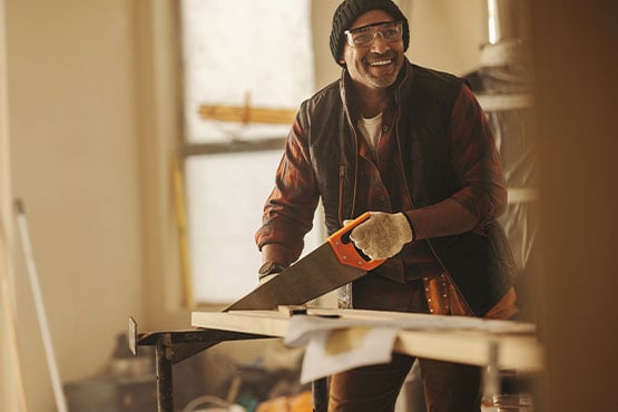 Laughing contractor and local business owner cuts wood trim for a kitchen remodel in Fargo, ND