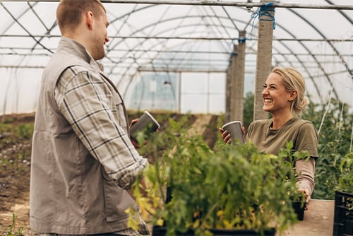 Young couple laughing while drinking coffee in to-go cups at a greenhouse in Mohall, North Dakota