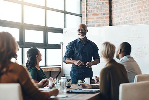 Laid-back businessman with a gray beard leading a meeting inside a brick building in Bismarck, North Dakota