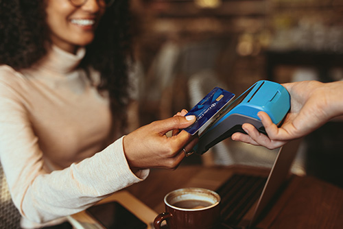 curly-haired woman taps her debit card to pay for a latte at a Grand Forks, ND, coffee shop using Gate City Bank merchant services