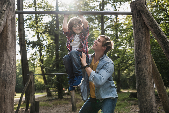 parent and child play together with a backyard playset on a sunny day