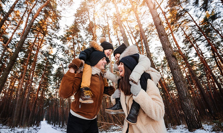 Laughing mom and dad with two kids, walking through Carlos State Park in winter gear near Alexandria, MN