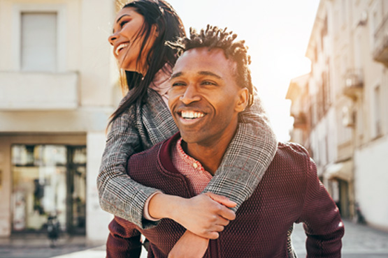 Young man giving his girlfriend a piggyback ride in downtown Fargo, ND, on the way to meet their Gate City Insurance advisor