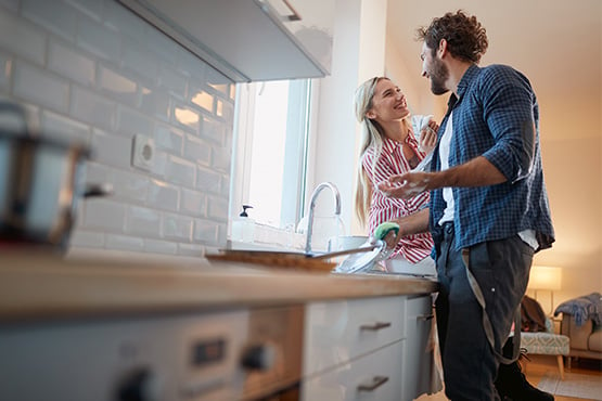 a happy couple washes dishes in their newly remodeled kitchen after learning about home improvements with the best return on investment (ROI) from Gate City Bank