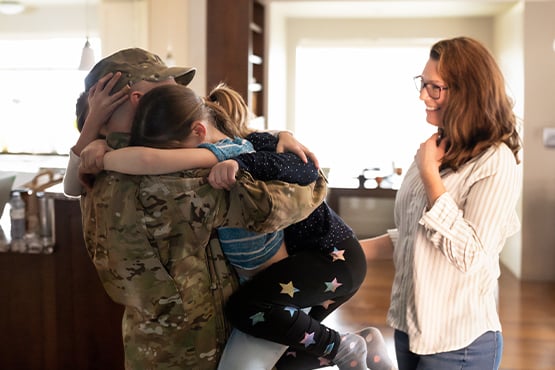 Military service member in Fargo hugs his two kids, while his wife tries to hold back tears in their home purchased with a VA loan