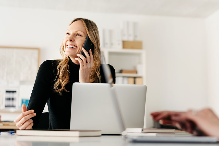 Laughing blond businesswoman, talking on the phone in her office in West Fargo, North Dakota