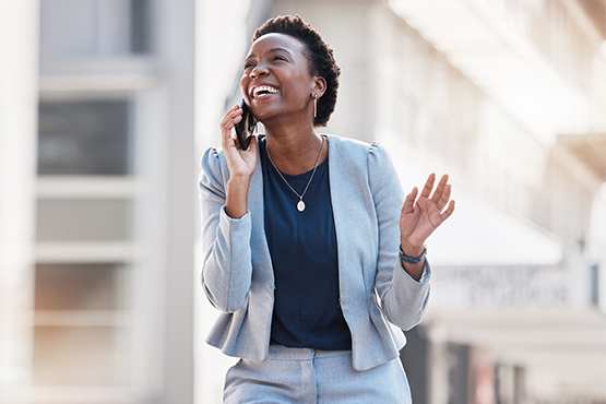 Laughing businesswoman in a gray suit, talking on the phone with her Gate City Bank business banker in downtown Fargo, ND