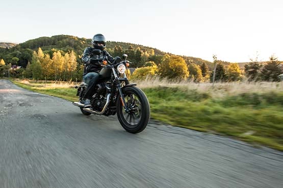 Motorcycle rider in helmet cruises a backroad at sunset near Alexandria, Minnesota