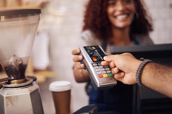 close-up of Gate City Bank business debit card being used by a small business owner paying for coffee on a business trip