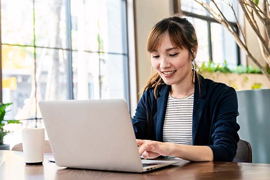 happy young woman works at desk laptop and examines best IRA accounts with Gate City Bank