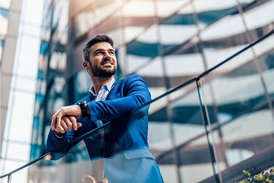 happy businessman in blue suit in front of a glass building in Fargo, ND, after opening a business high yield savings account