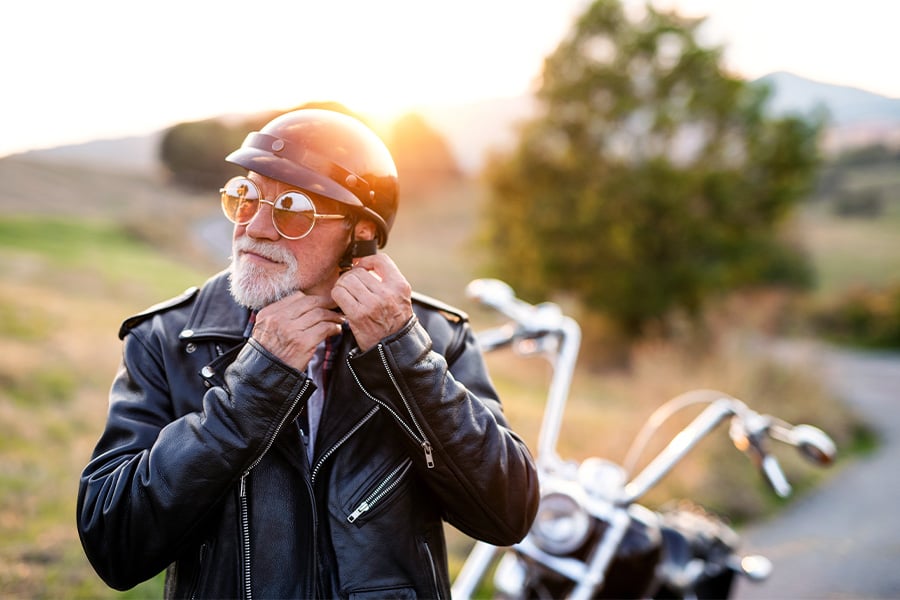 silver-haired biker at sunset in ND, unbuckling his helmet after riding a chopper thanks to a Gate City Bank motorcycle loan