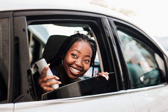 a happy woman glances out of a car window after reading Gate City Bank’s insights for determining the best time to buy a car