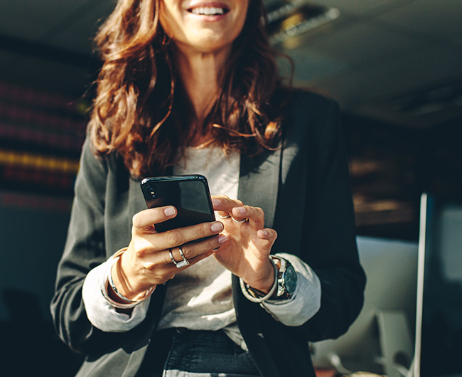 Close-up of young realtor in Bismarck, ND, smiling while using business mobile banking with Gate City Bank’s app