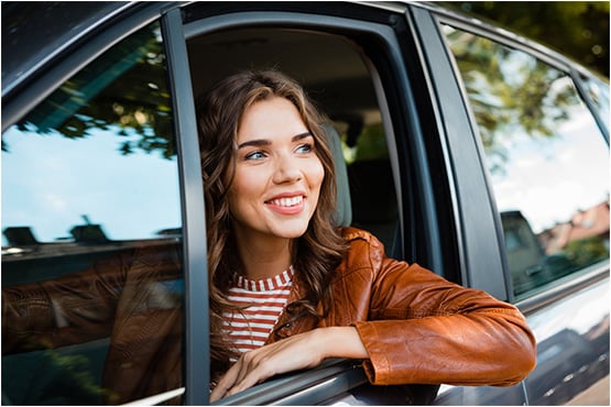 a joyful woman leans out of her car window after asking, how much car can I afford, and learning insights from Gate City Bank