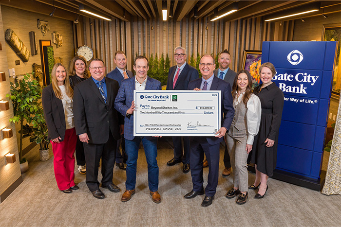 a Beyond Shelter representative and Gate City Bank team members smile for the camera while holding a big check for $250,000