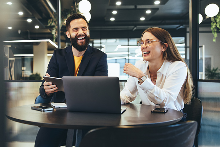 Two professionals in downtown Fargo, ND, laughing and talking while making a remote deposit from the office after business hours