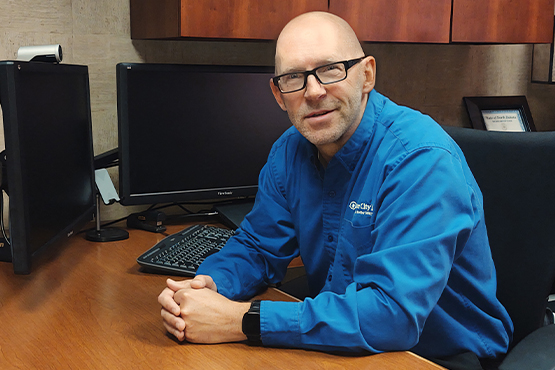 team member Darryl Jorgenson sits at desk in his office