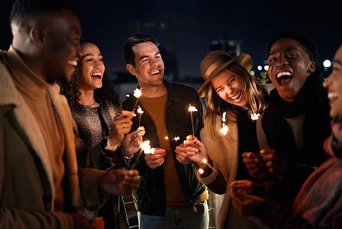 Group of friends laughing in downtown Fargo, ND, holding sparklers to celebrate opening their new Gate City Bank checking accounts