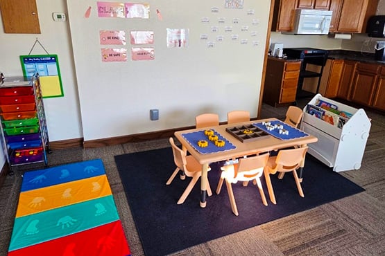 Interior view of Little Blessings Academy classroom with playmats, books and tables for young children in Bismarck, ND.